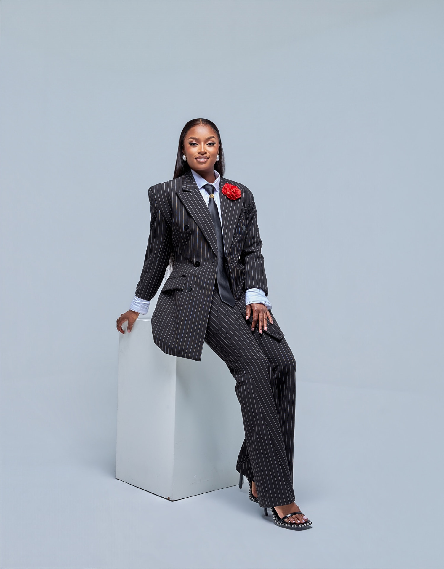 Musa Yende in a black pinstripe suit with a red rose